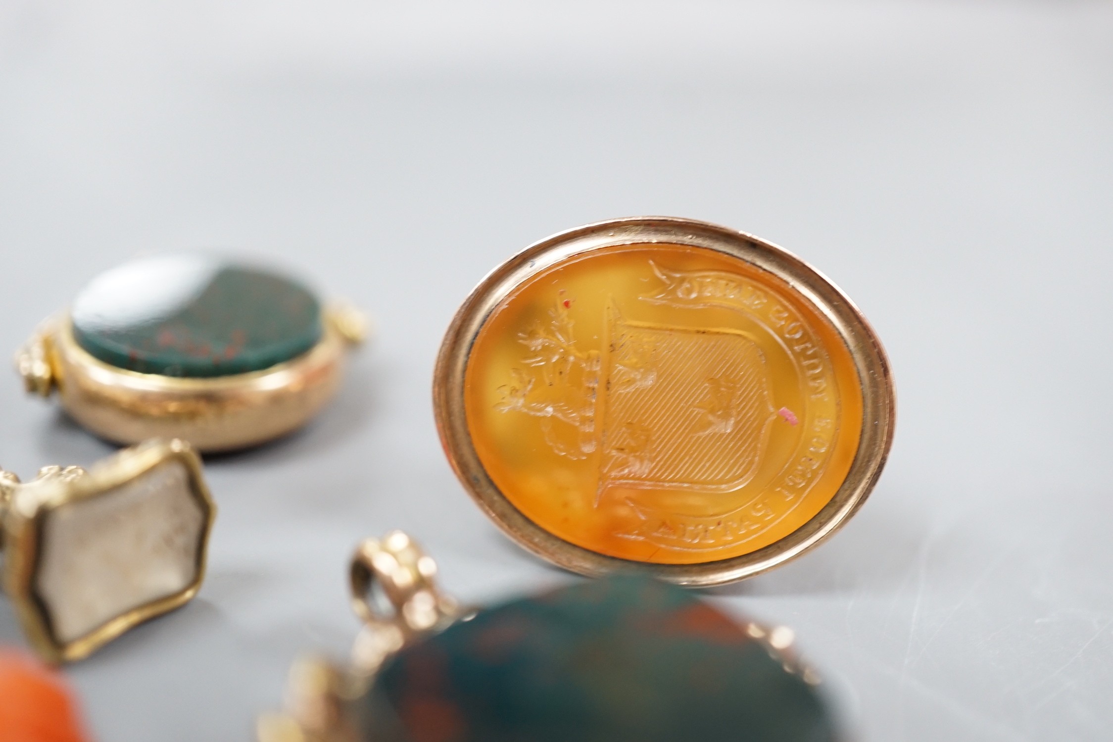 Six assorted late 19th/early 20th century gem set fob seals, including yellow metal overlaid with red intaglio stone carved with Roman soldiers, two 9ct gold, carnelian and bloodstone and a carnelian carved with family c